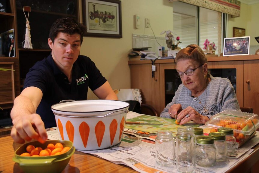 Dave Weir and his grandmother Phyllis Forbes sitting at a table preparing the fruit.