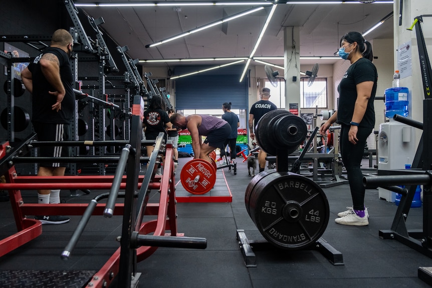 people at a gym lifting weights and standing around