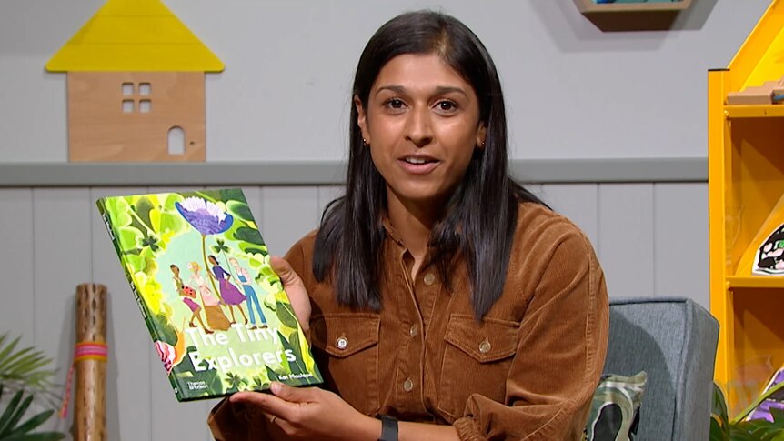 Teacher Vindhya Singh holds up story book, The Tiny Explorers