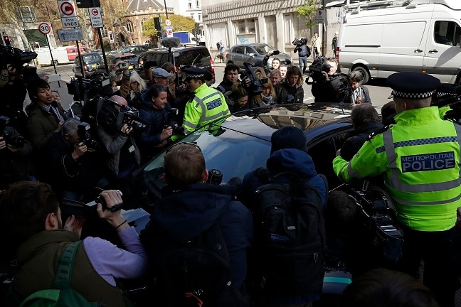 Media waiting for the arrival of WikiLeaks founder Julian Assange swarm around a car.