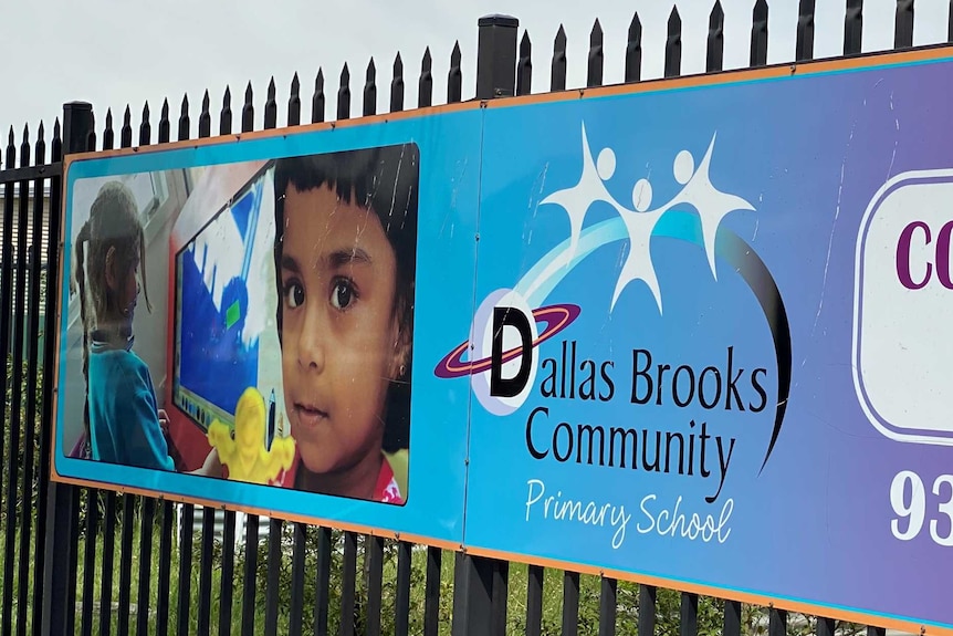 A sign on a fence says 'Dallas Brooks Community Primary School'.