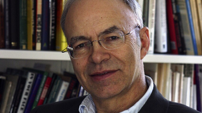 Peter Singer wearing glasses in front of a bookshelf