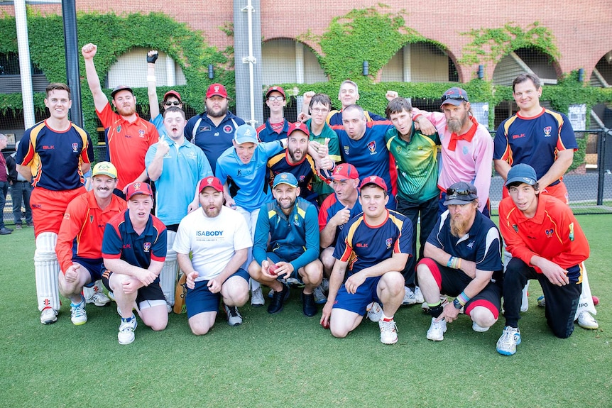 A large group of young sportspeople pose for a photo outside a sports venue. At the centre is cricketer Nathan Lyon.