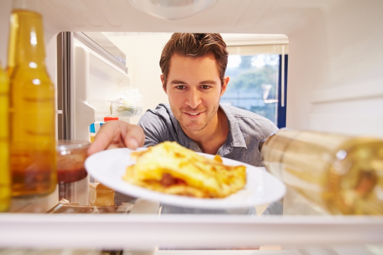 A man looking into a fridge for leftovers