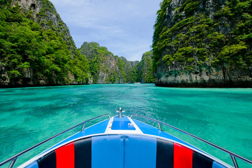 A boat cruises in crystal blue waters in Thailand