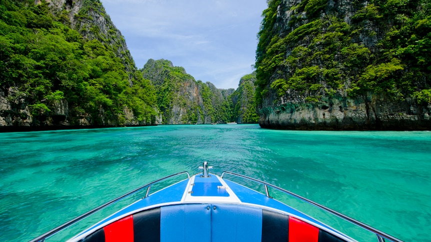 A boat cruises in crystal blue waters in Thailand