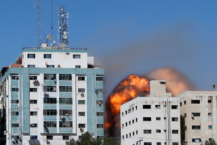 Flames arise from a Gaza building housing media hi by an Israeli air strike