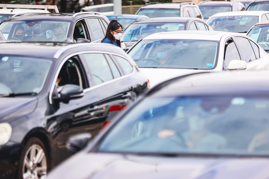 People in cars wait for a covid test