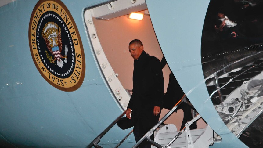 President Barack Obama steps off Air Force One at night.