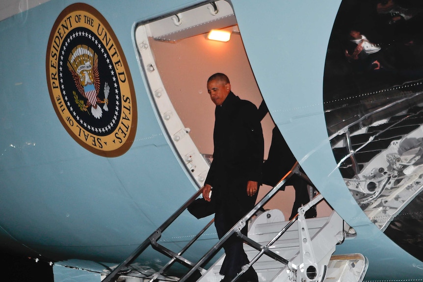 President Barack Obama steps off Air Force One at night.