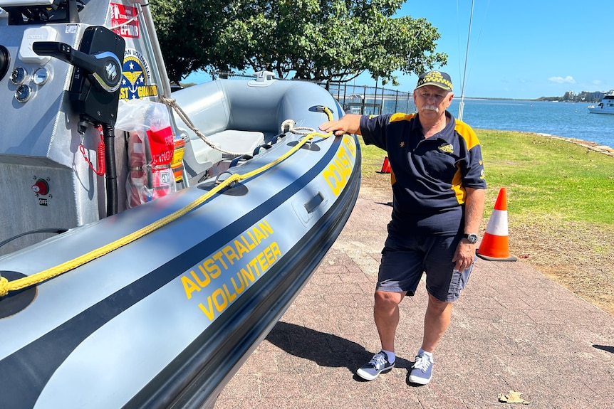 A uniformed man stands next to a rescue boat.