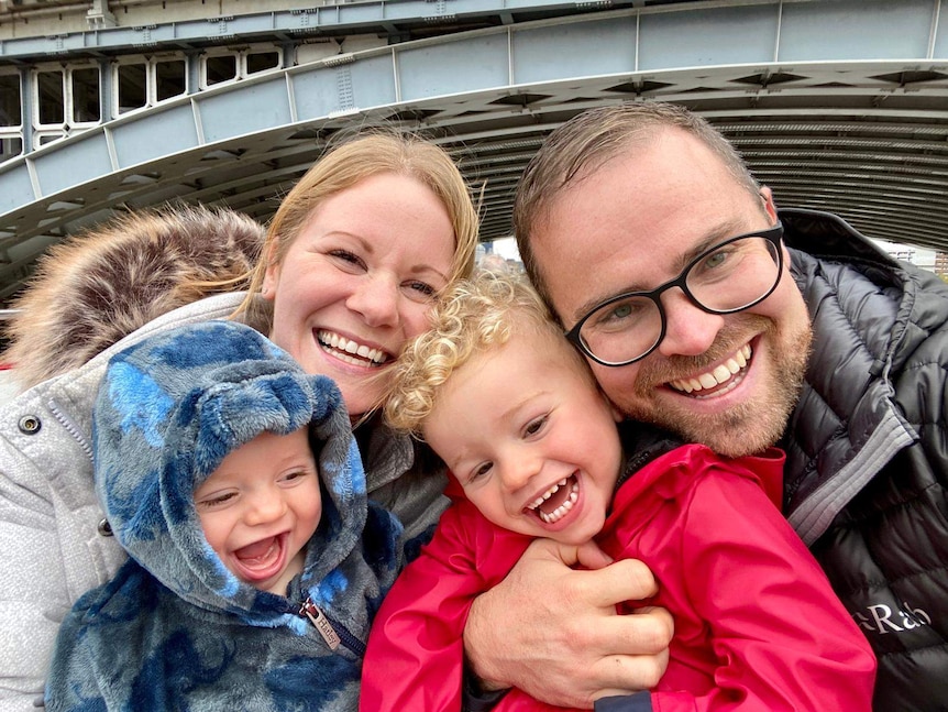 A mum and dad on a boat with their two young children with beaming smiles