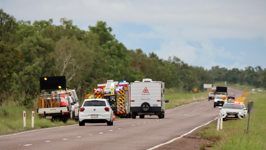 emergency services attend a scene on a road lined with green trees