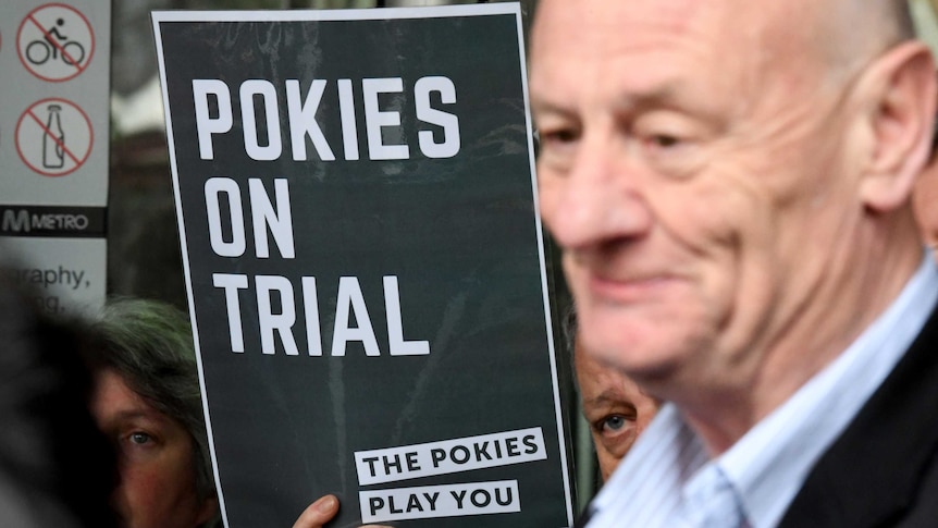 Australian Baptist minister Tim Costello stands next to a Pokies on Trial sign.