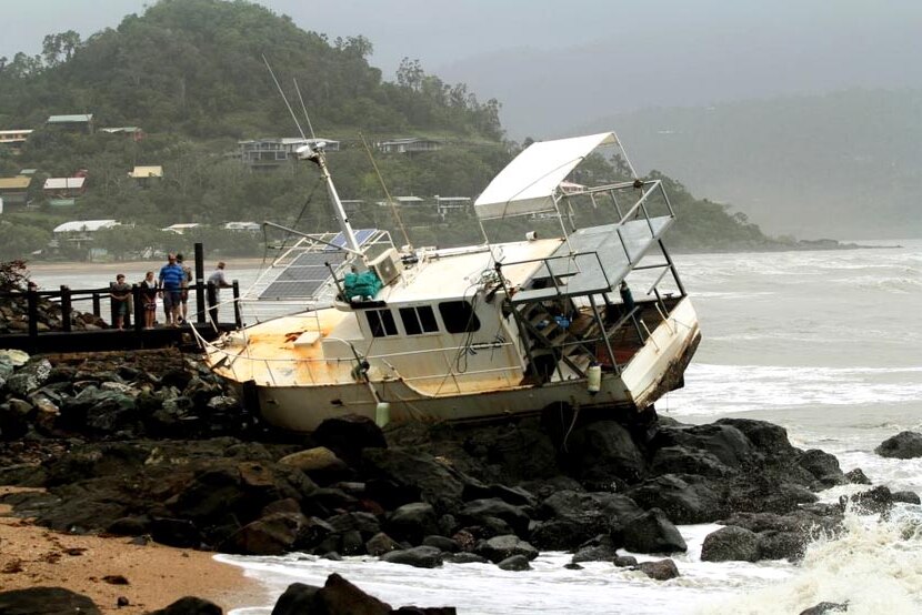 A boat sits on rocks at Airlie Beach after gale force winds dragged it from its mooring.