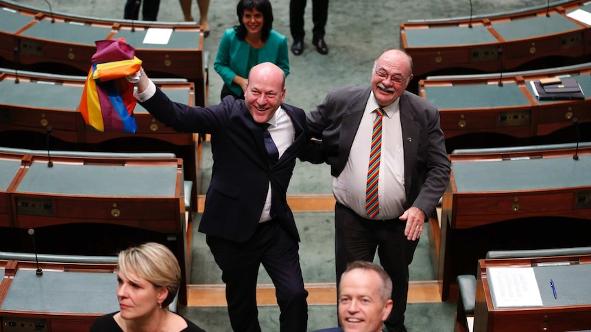 Trent Zimmerman, waving a rainbow flag and grinning from ear to ear, has his arm around Warren Entsch, wearing a rainbow tie