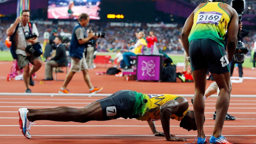 Usain Bolt does push-ups next to Yohan Blake as he celebrates winning the men's 200m final.