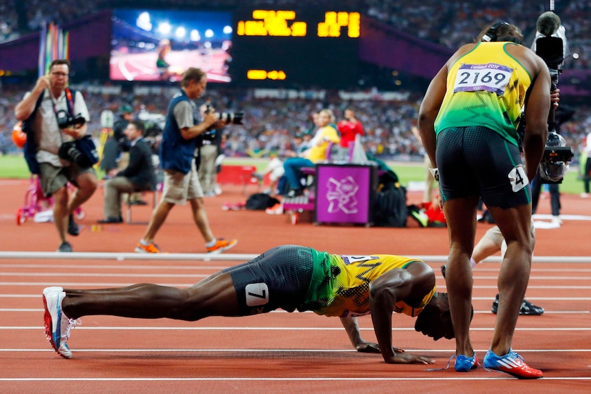 Usain Bolt does push-ups next to Yohan Blake as he celebrates winning the men's 200m final.