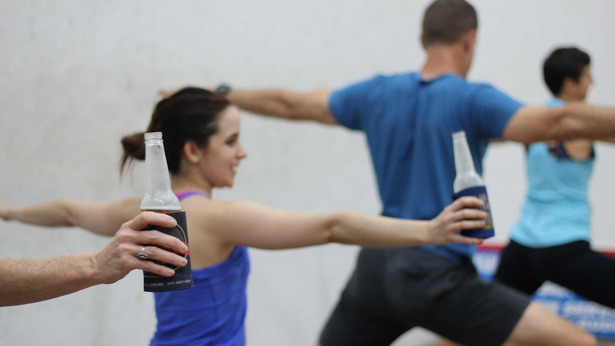 Four people practice yoga with a beer in their hands