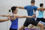 Four people practice yoga with a beer in their hands