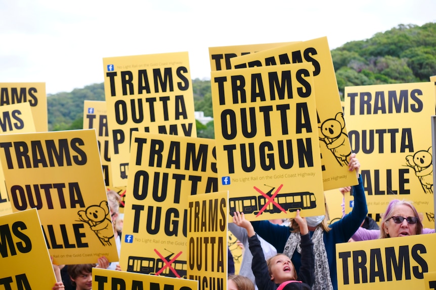 Protesters hold signs saying "Trams outta Tugun".