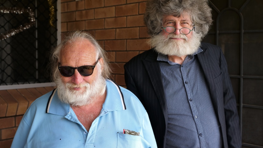 Gary wearing dark sunglasses, light blue shirt next to Garry, who is wearing a dark blue shirt and jacket.