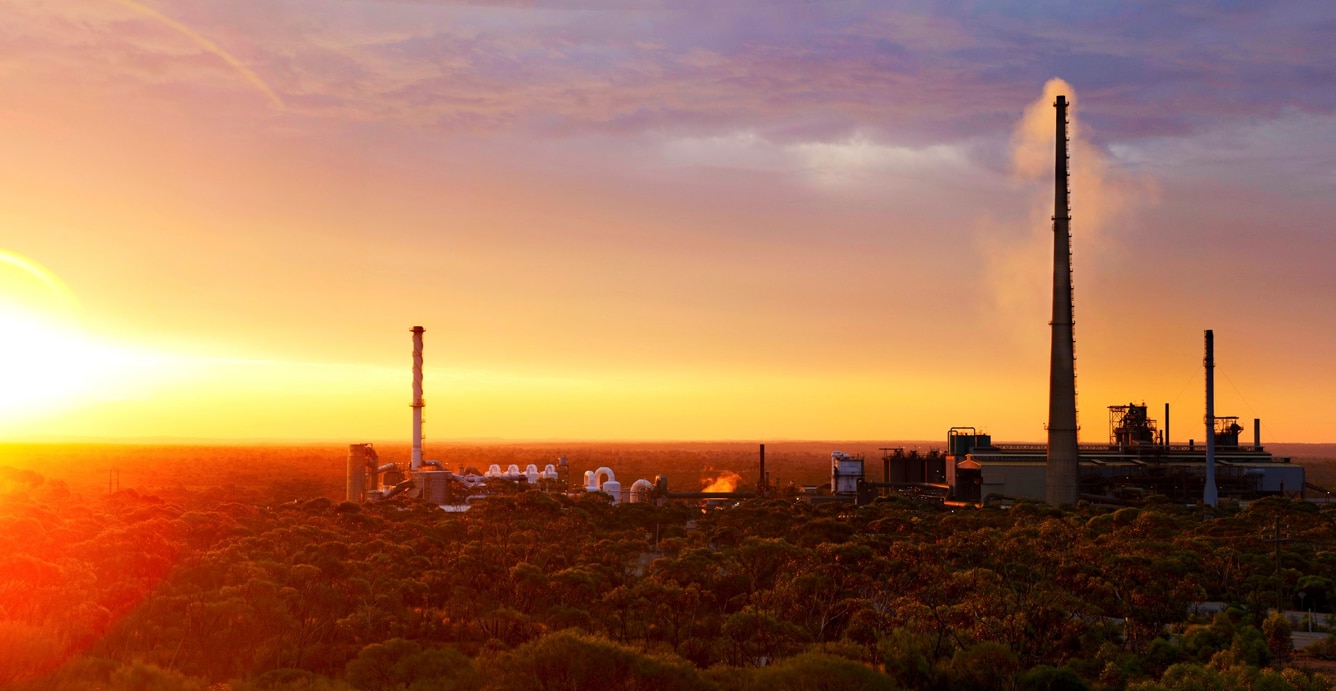 Sunset at a mining operation with a big smoke stack.  