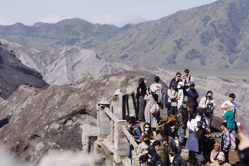 People look into a volcano over a railing.