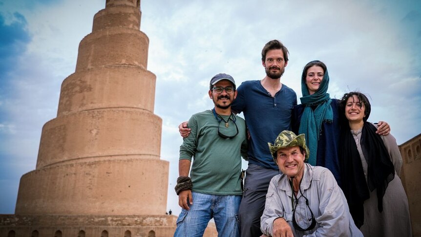 Group of 5  men and women, Westerners and Iraqis, grouped in front of a spiral tower