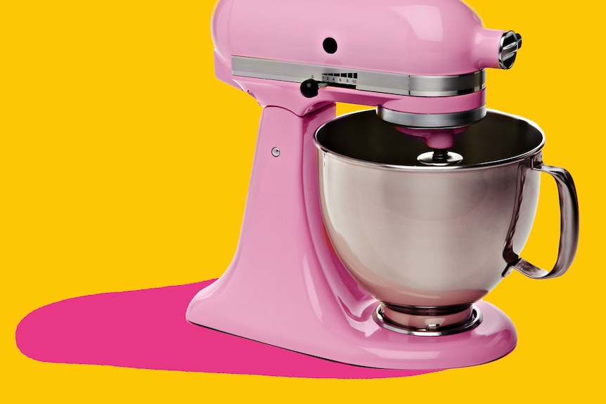 A pastel pink stand mixer is seen cut out against a yellow and pink background.