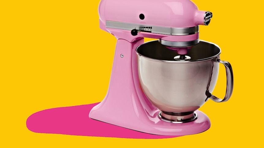 A pastel pink stand mixer is seen cut out against a yellow and pink background.