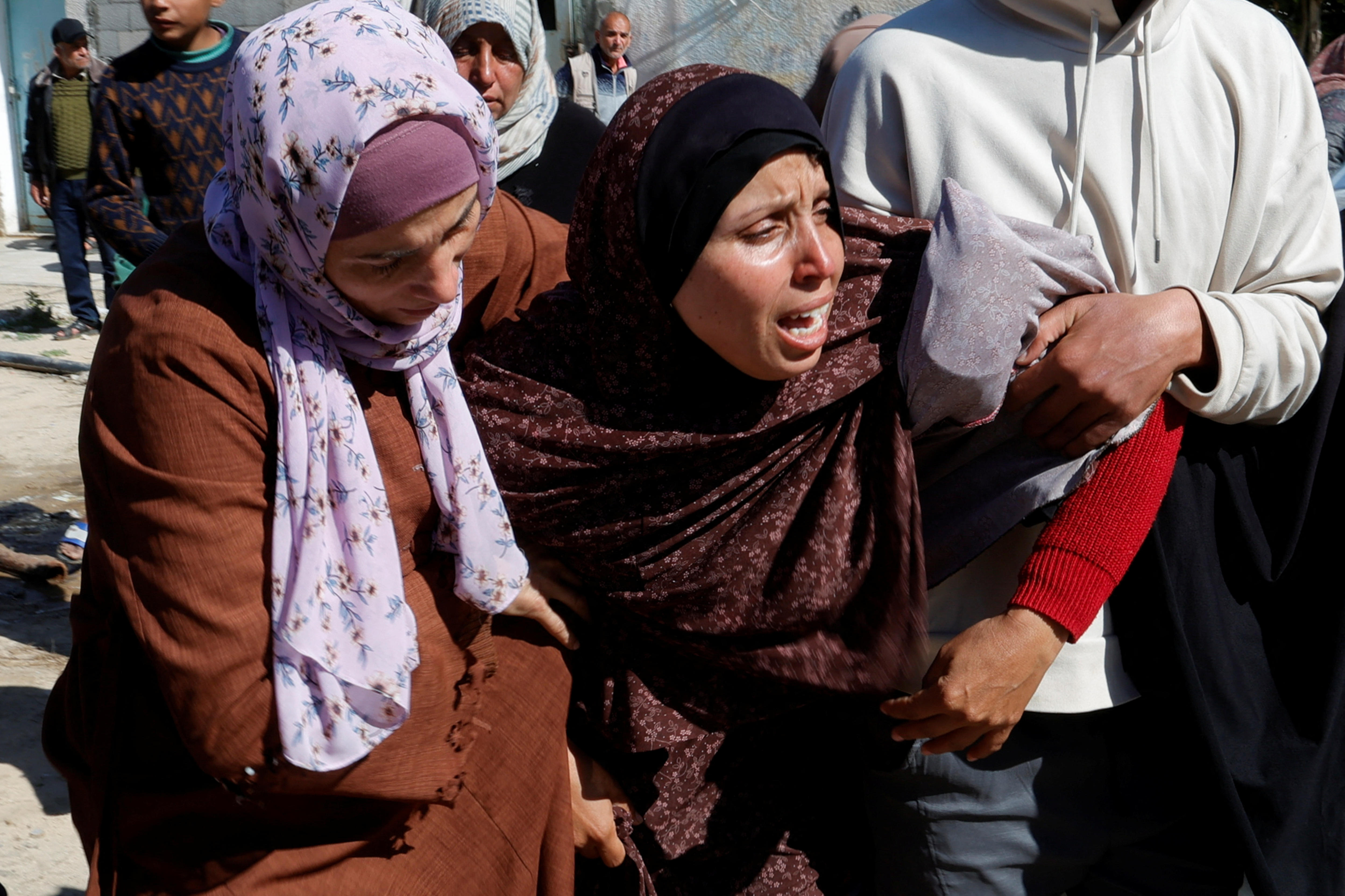 A woman cries as two other women support her on each side