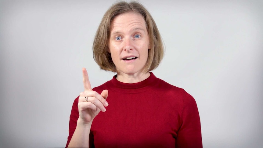 A woman points her index finger in the air while singing.