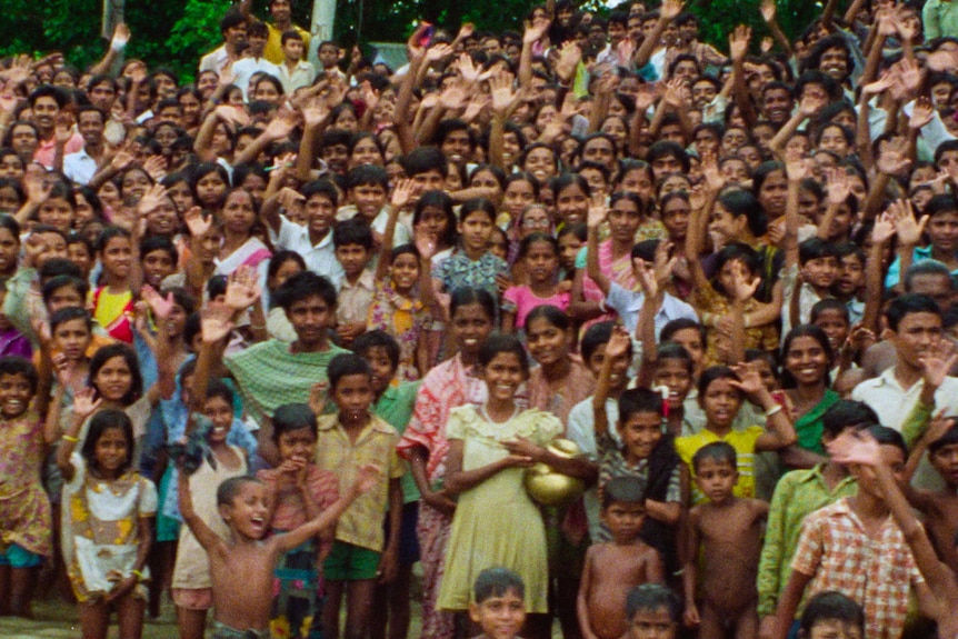 A large crowd gathers in India on the banks of a river.