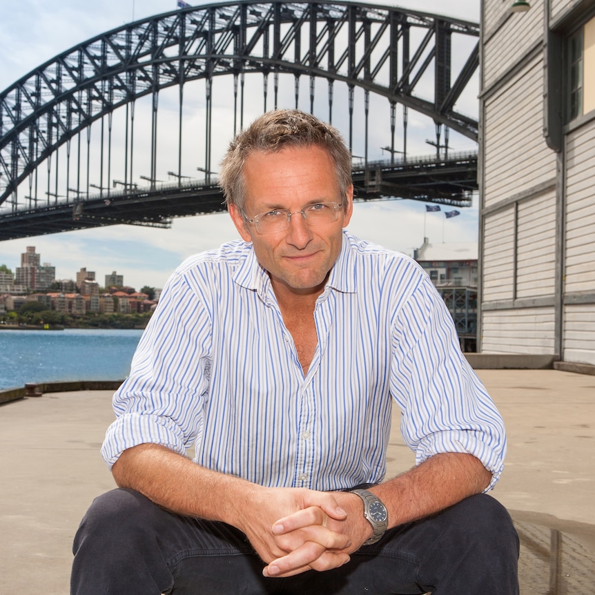 Michae Mosley sits on the steps and poses for a photo with the Sydney Harbour Bridge behind him