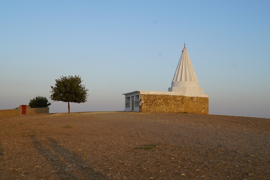 A building with a white pointed roof built in an empty field