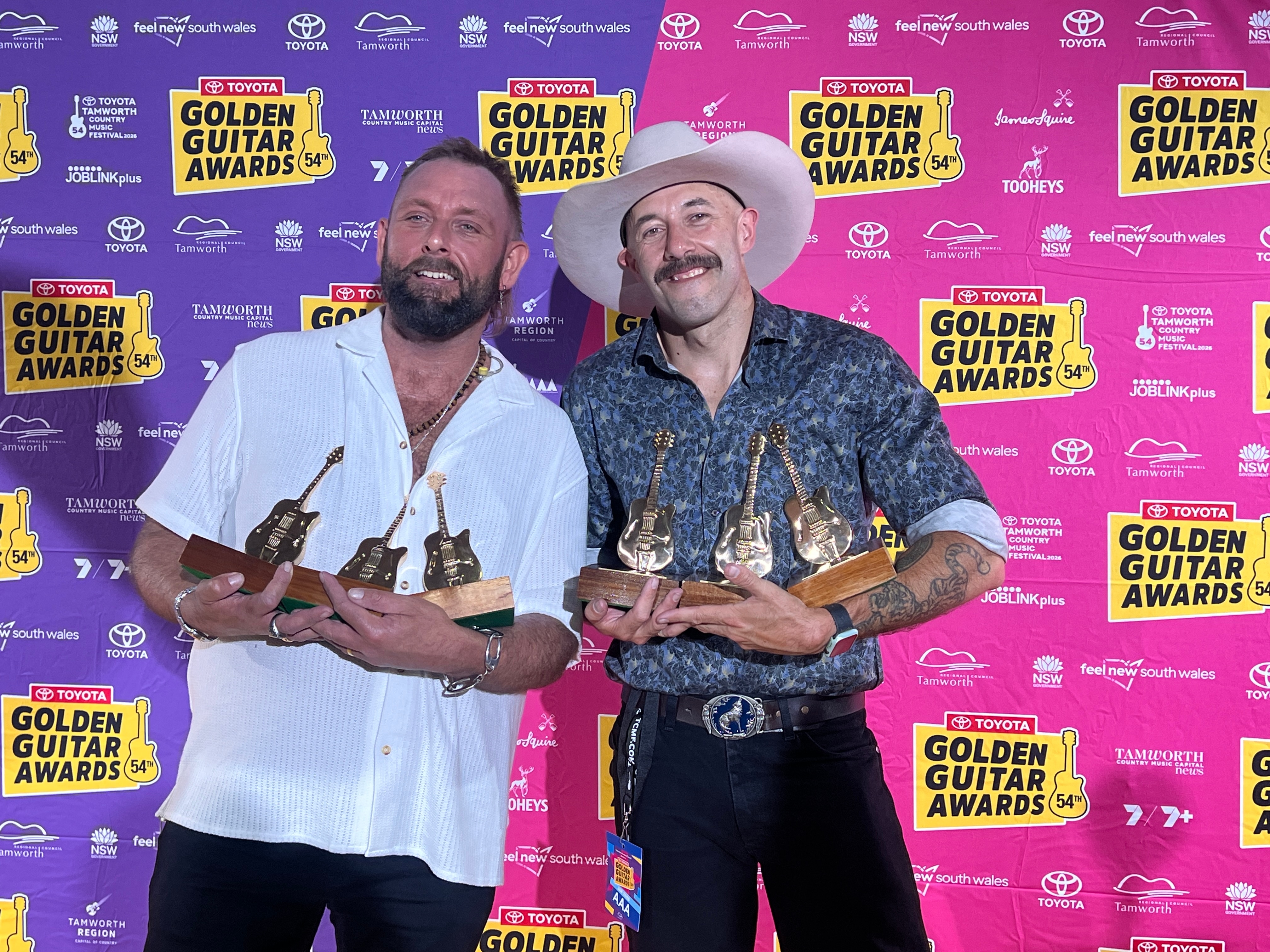 Dois homens com prêmios de guitarra de ouro.