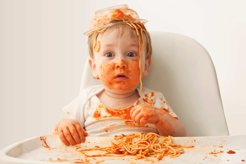 Baby boy eating spaghetti