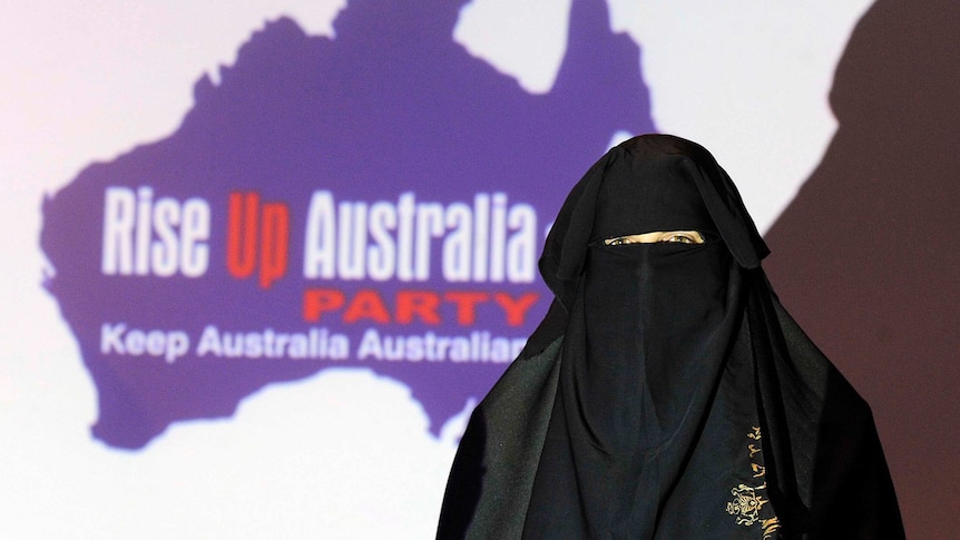 A person stands in traditional Muslim clothing at the campaign launch