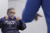Colour still image from 2018 documentary RBG of Ruth Bader Ginsburg working out with dumbbells and a jumper.