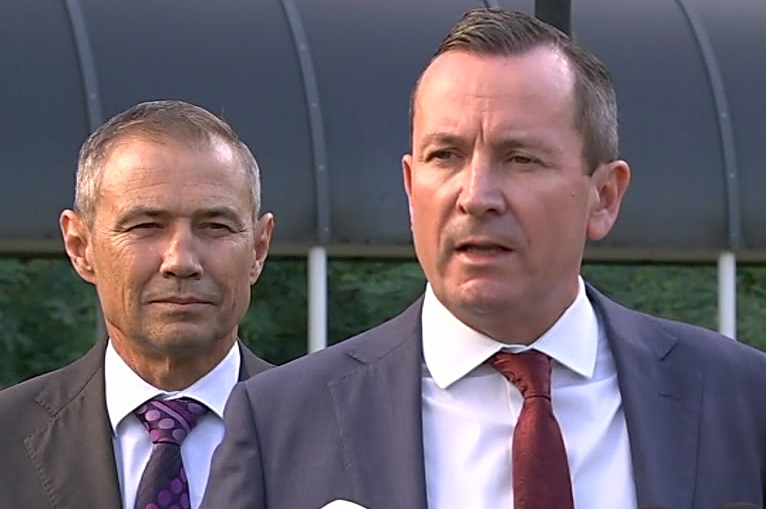 Mark McGowan speaks into microphones at a press conference as Roger Cook stands in the background.