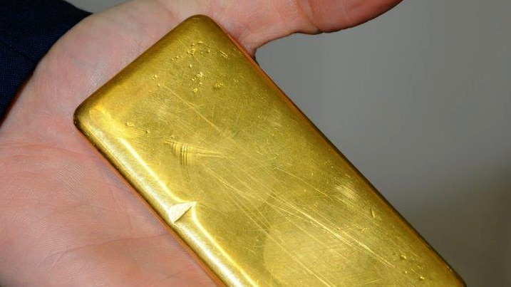 Police officer holds a one kilogram gold bar