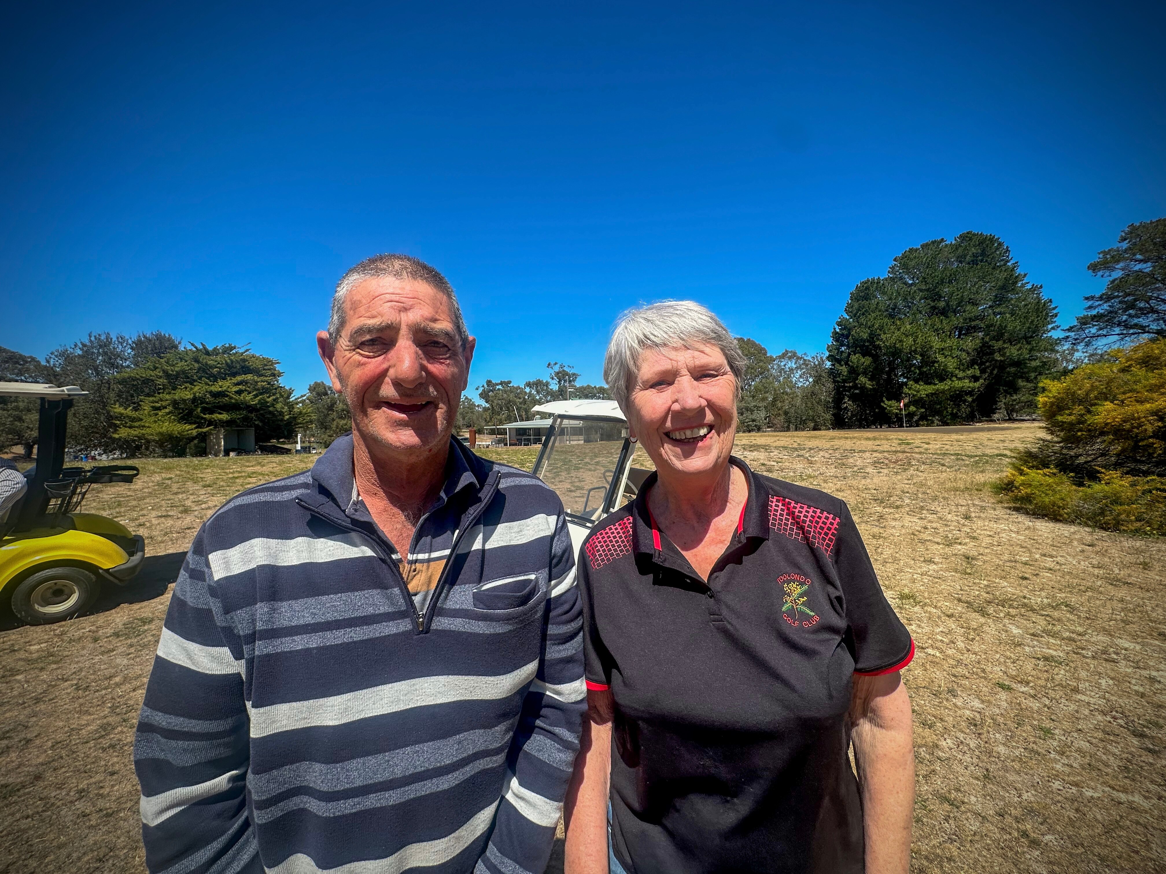 Man and woman smiling at golf course while standing side by side