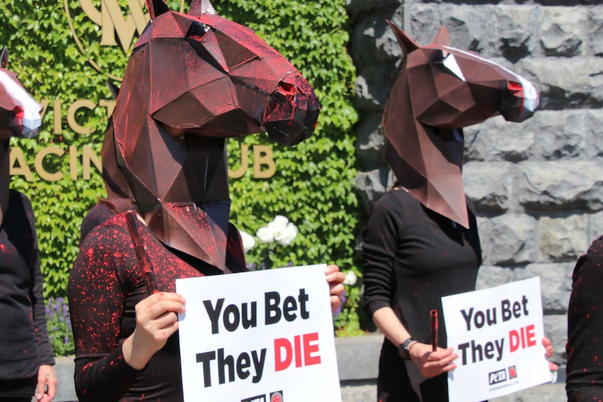 People wearing horse head masks with signs saying you bet, they die.
