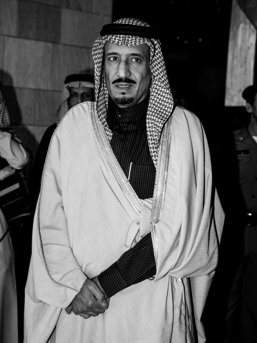A black and white photo of a middle-aged Arabic man with a chequered head cover.
