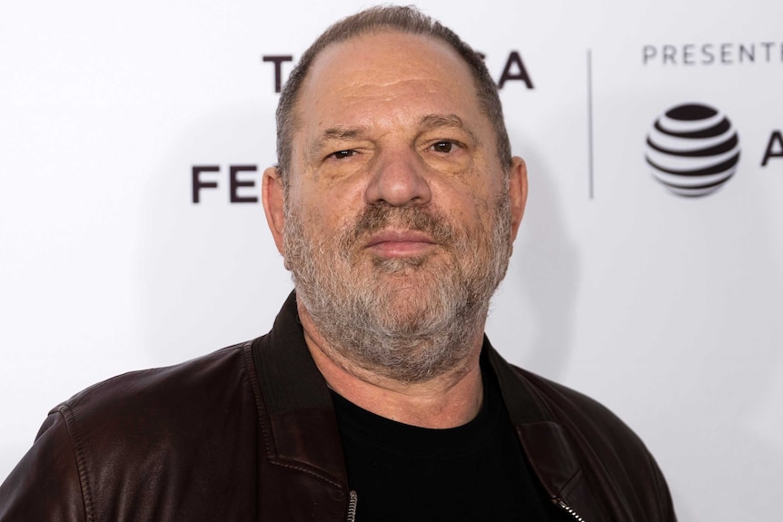 Harvey Weinstein grins as he looks directly into the camera with a grey beard.