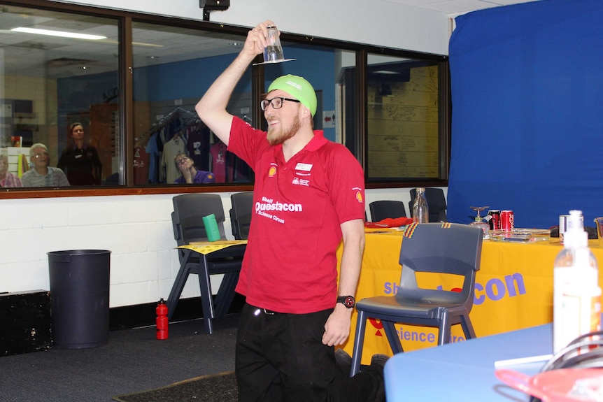 A picture of a man with a cup over his head. The cup holds water. He is performing a science experiment.