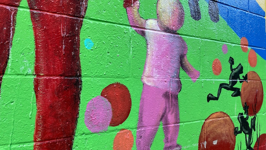 Mural on a brick wall of a child holding an adult's hand.