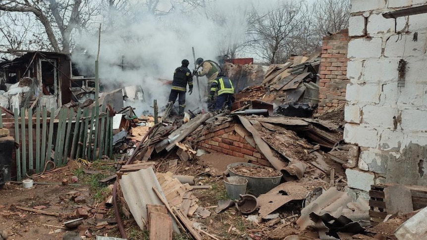 Fire fighters work in an area destoryed by a drone attack.