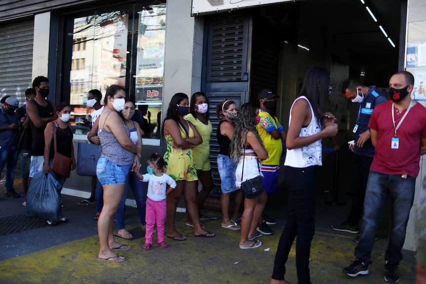 People wearing masks line up for temperature checks before being tested for COVID-19.